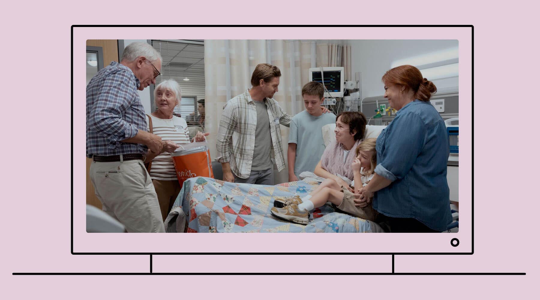 Una ilustración de un televisor. En la pantalla del televisor, se ve una foto de la serie The Pitt de HBO Max, donde una familia se reúne alrededor de una mujer en la cama de un hospital. Están a punto de compartir un helado. Todos están tristes, pero sonríen.